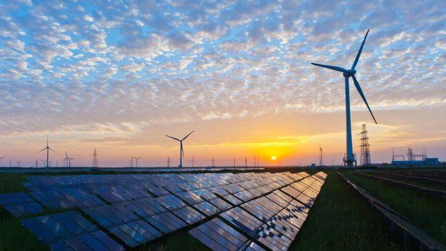 Solar panels and wind turbines at sunset