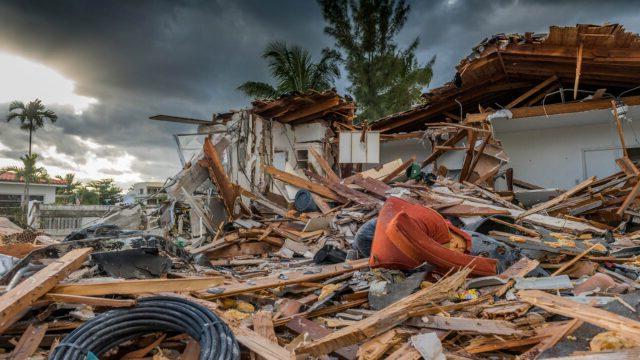 A pile of building debris caused by Hurricane Matthew with sun setting in background